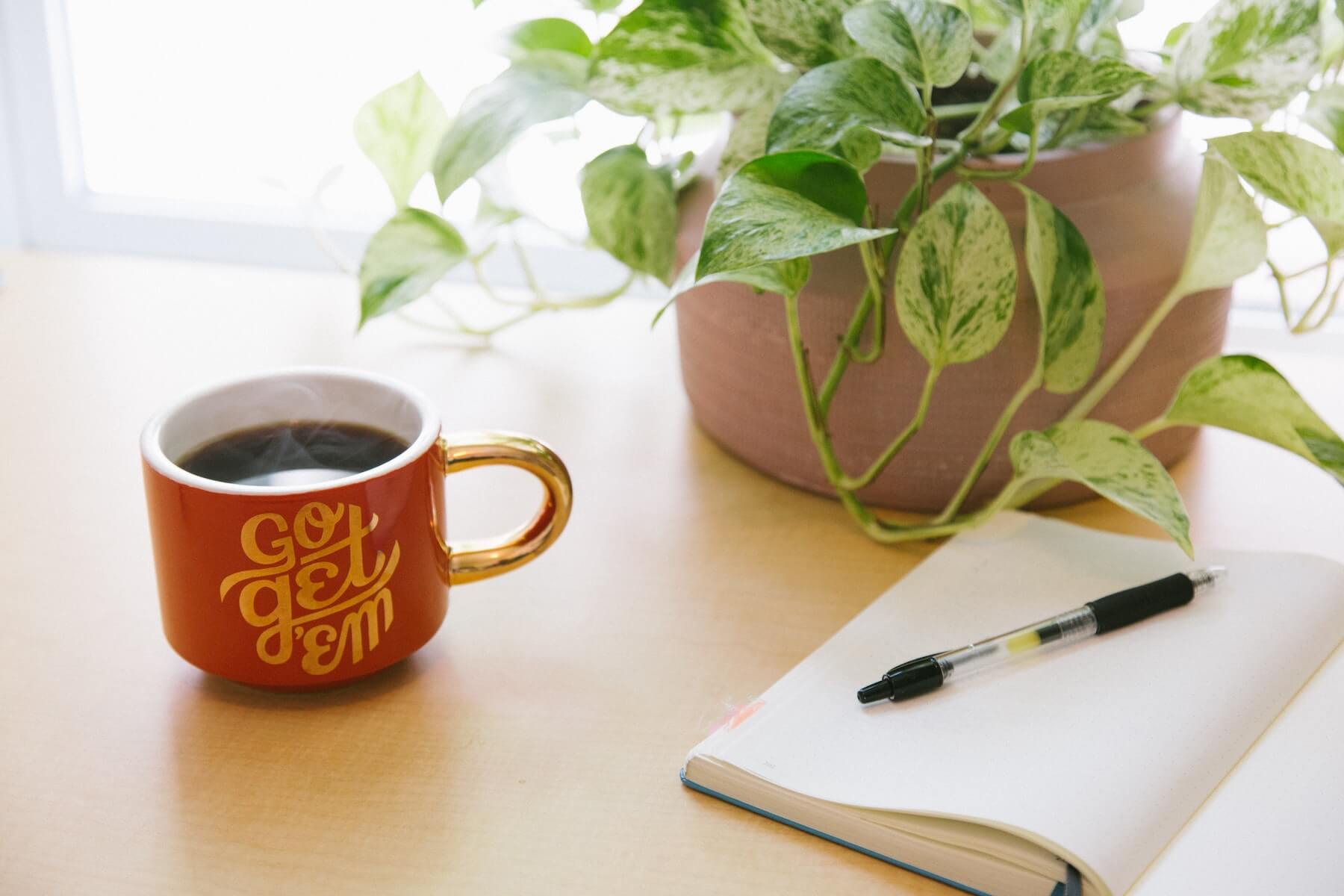 plant coffee cup and pen and paper on table side hustles for nurses