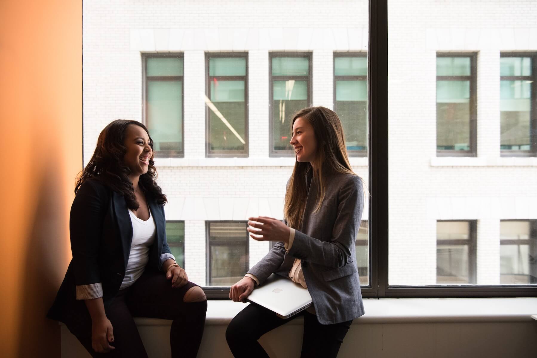 two woman sitting by window talking having conversations allyship in healthcare