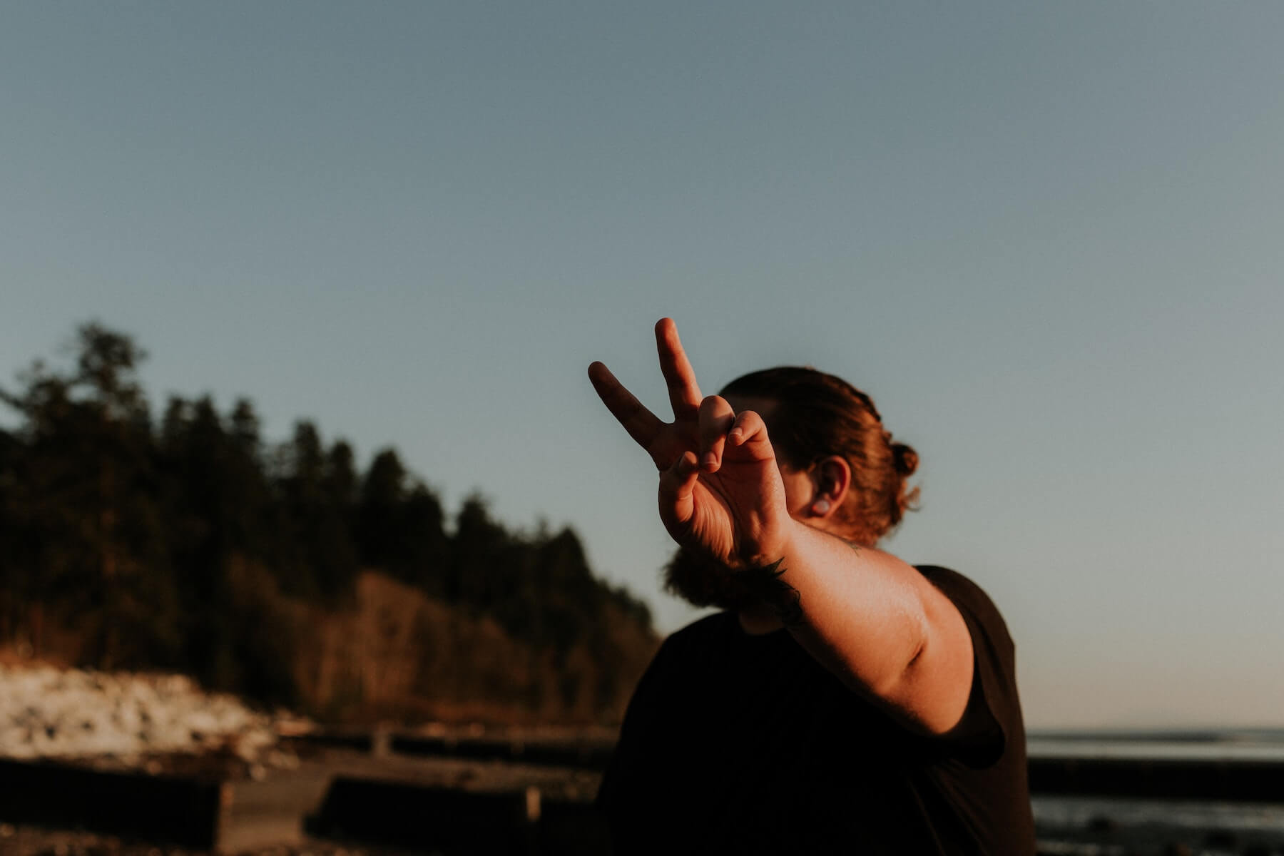 man giving peace sign with ocean behind him nurse wellness