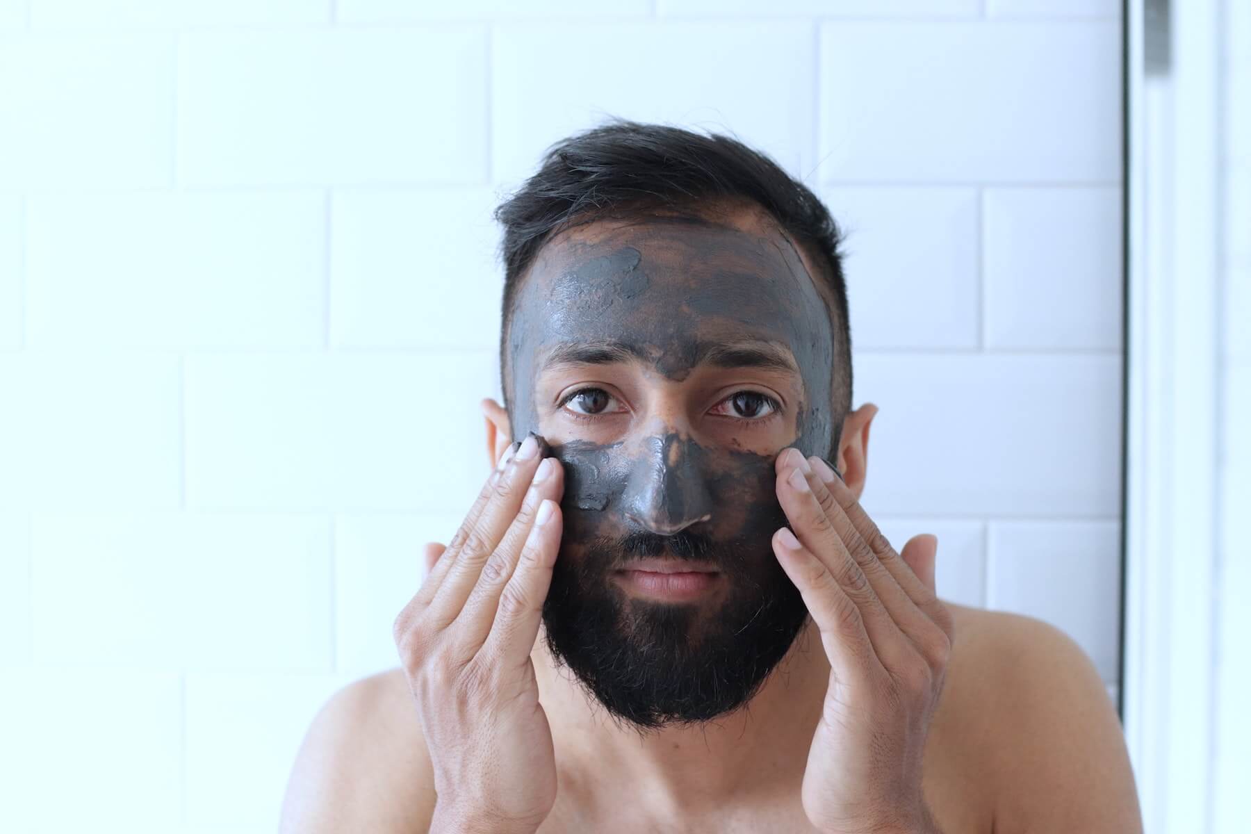 man looking in mirror applying face mask nurse skincare