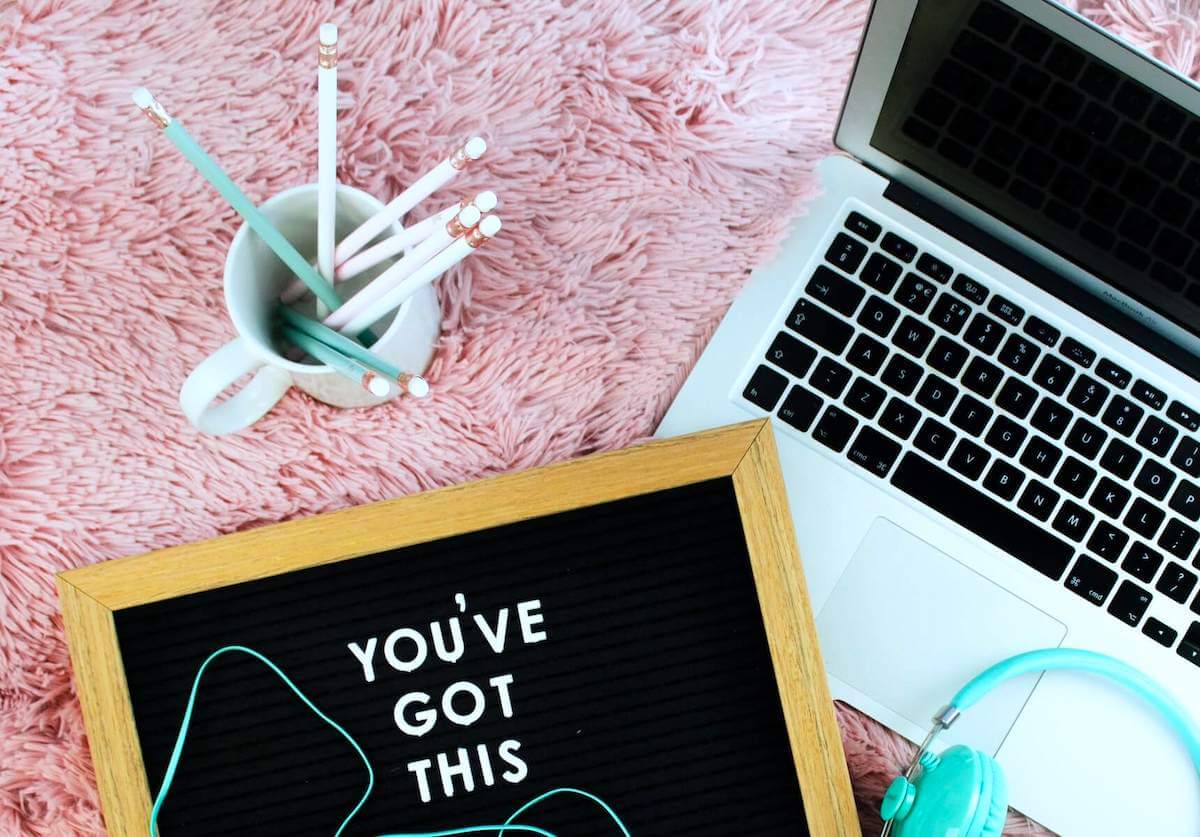 laptop notebook head phones and coffee mug with pencils in it sitting on pink carpet nursing cover letters