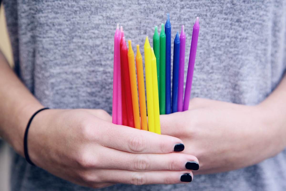 woman holding rainbow-colored candles allyship in healthcare