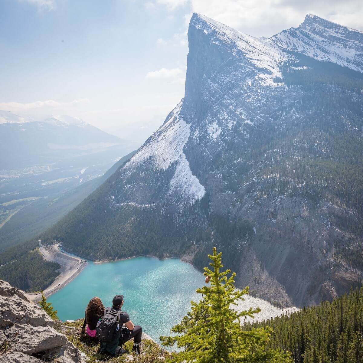 two people sitting on edge of cliff of mountain landscape travel nurses