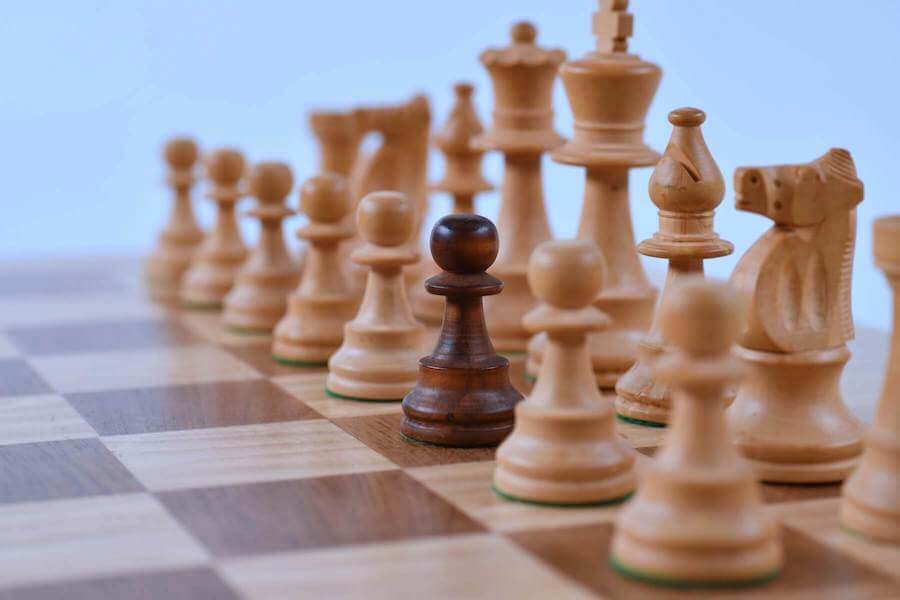 black chess piece in the middle of white chess pieces black nurse