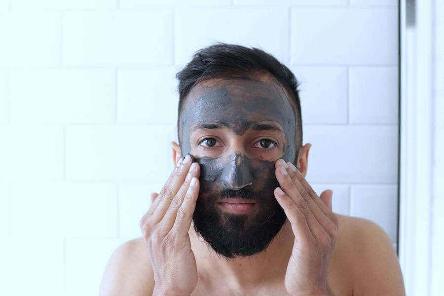 man looking in mirror applying face mask nurse skincare
