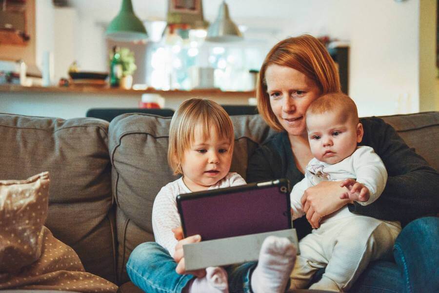 woman and two babies sitting on coach with tablet telemedicine