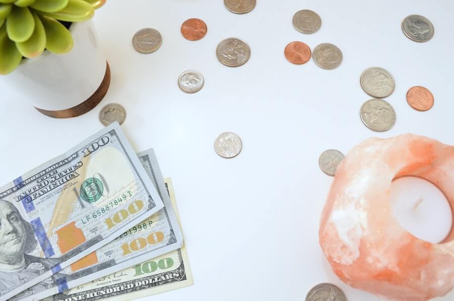 american money on white table next to candle and small plant top nursing blogs of 2020