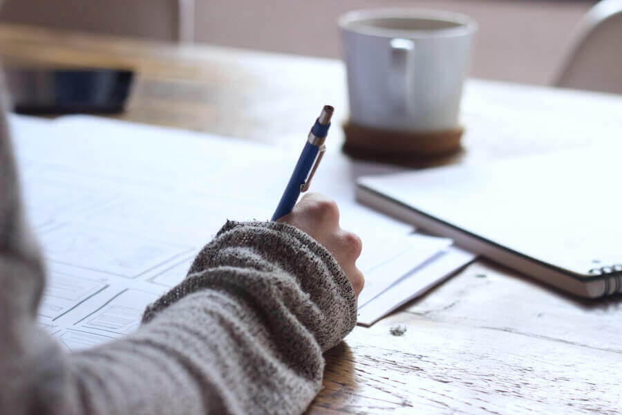woman working on nursing homework with pencil books and coffee on desk highest paying nurse practitioner specialties