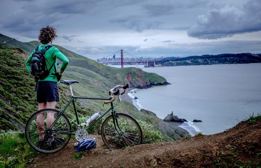 guy on bike on mountainside overlooking bay bridge travel nursing in a new city