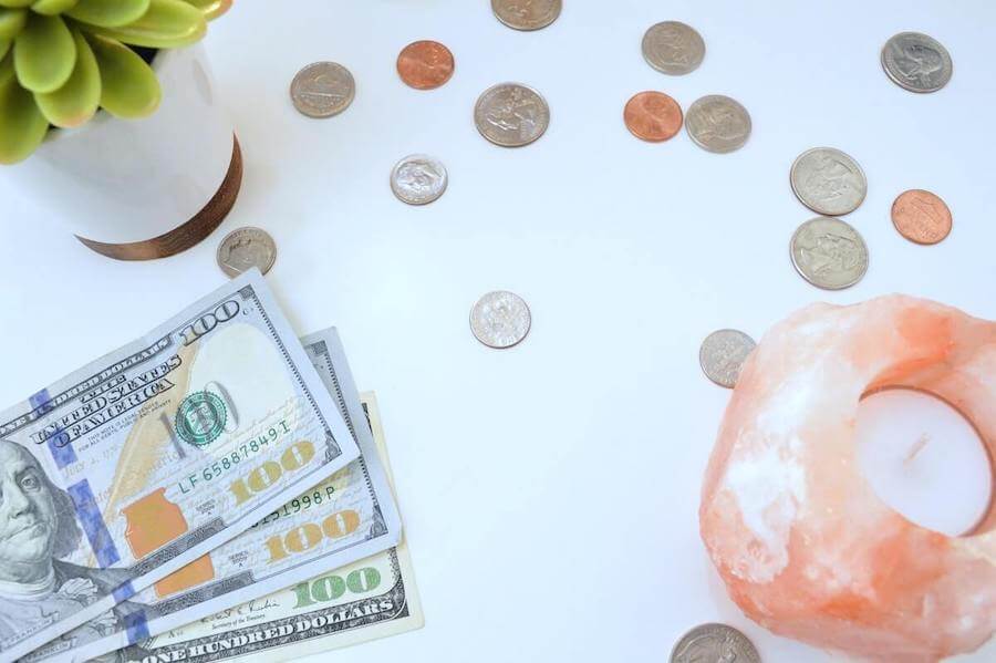 US bills and coins lying on table next to succulent and candle do nurses make a lot of money
