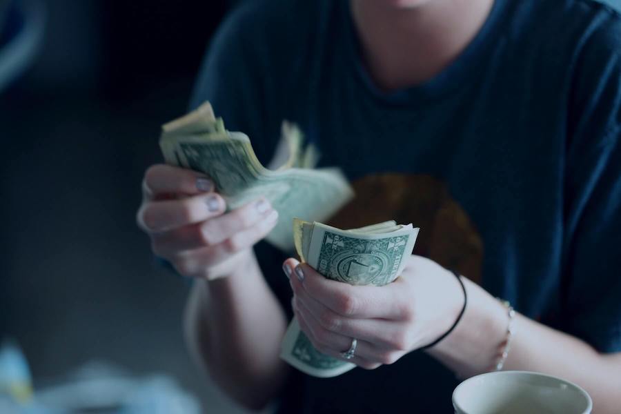woman flipping through dollar bills after selling scrubs nursing side hustles