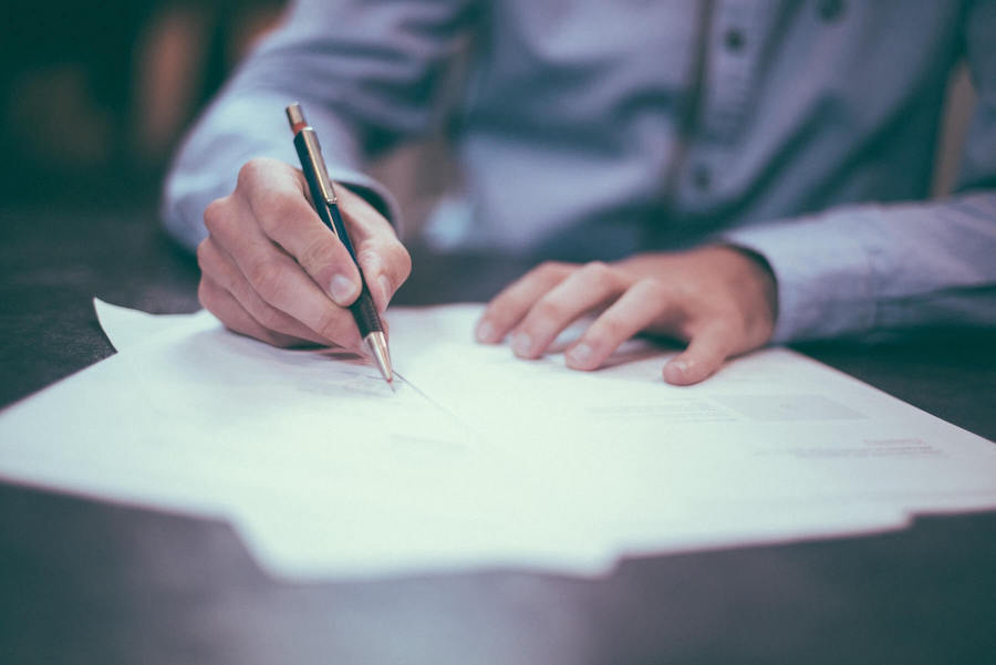 man holding pen looking at and writing on nursing resume