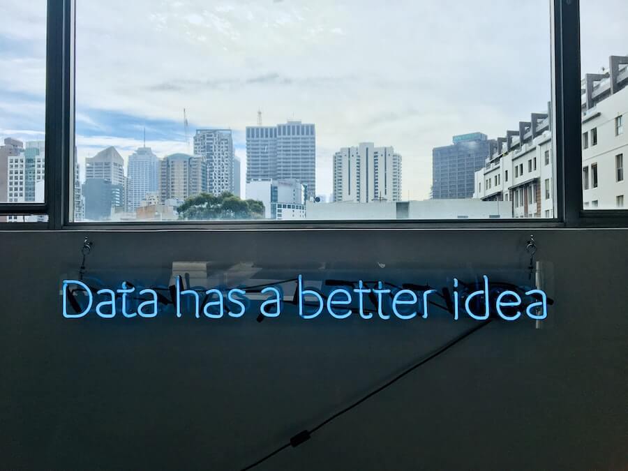 neon writing on inside of room below window looking out to skyscrapers data has a better idea informatics nurse