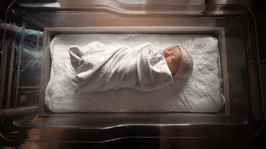 baby sleeping in hospital in open bin neonatal nurse