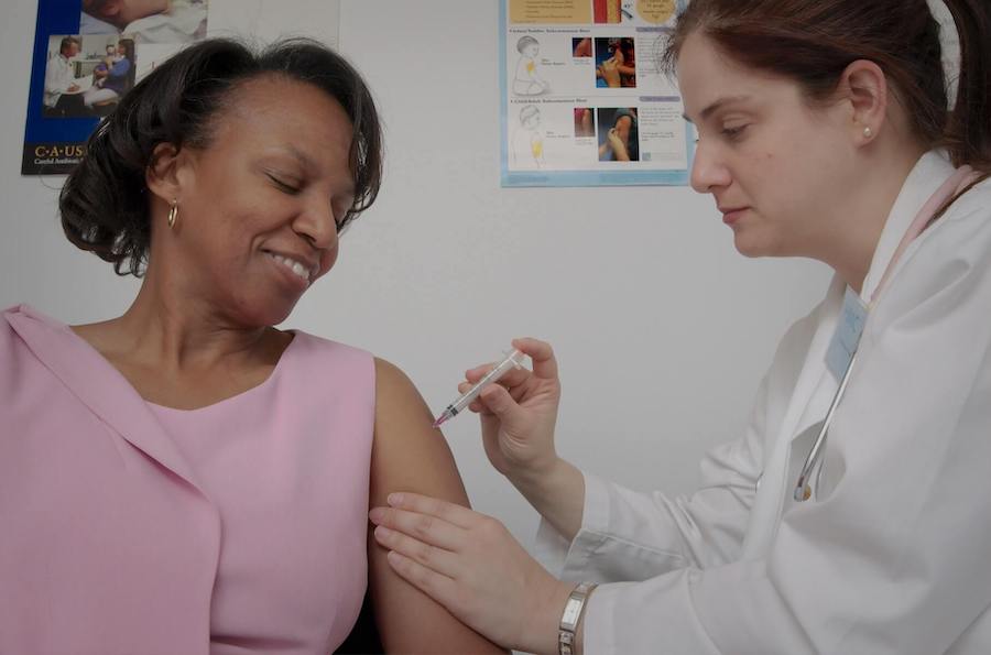 nurse practitioner gives shot to woman FNP