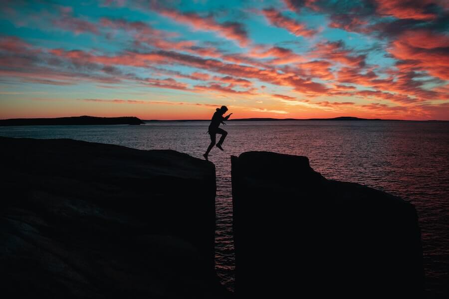 man jumping between rocks in front of sunset hardest parts of being a travel nurse