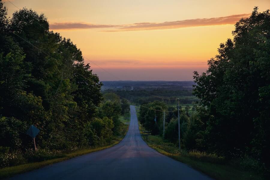 empty road in between trees stretching for miles travel nursing challenges