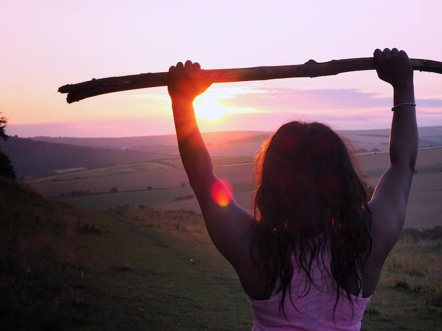 woman in front of landscape holding up stick athlete good habits hardest part of travel nursing