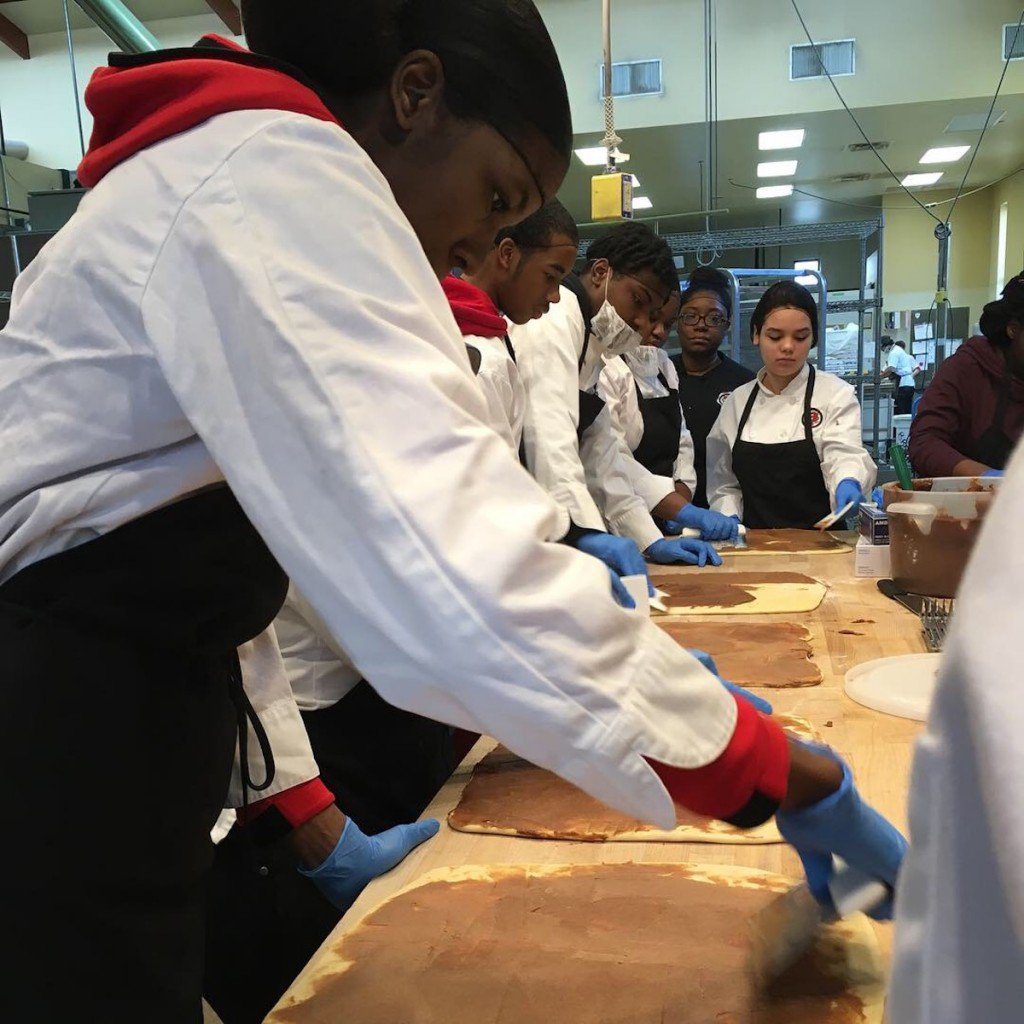MPS kids work on rolling out cinnamon rolls at Troubadour Bakery in Milwaukee.