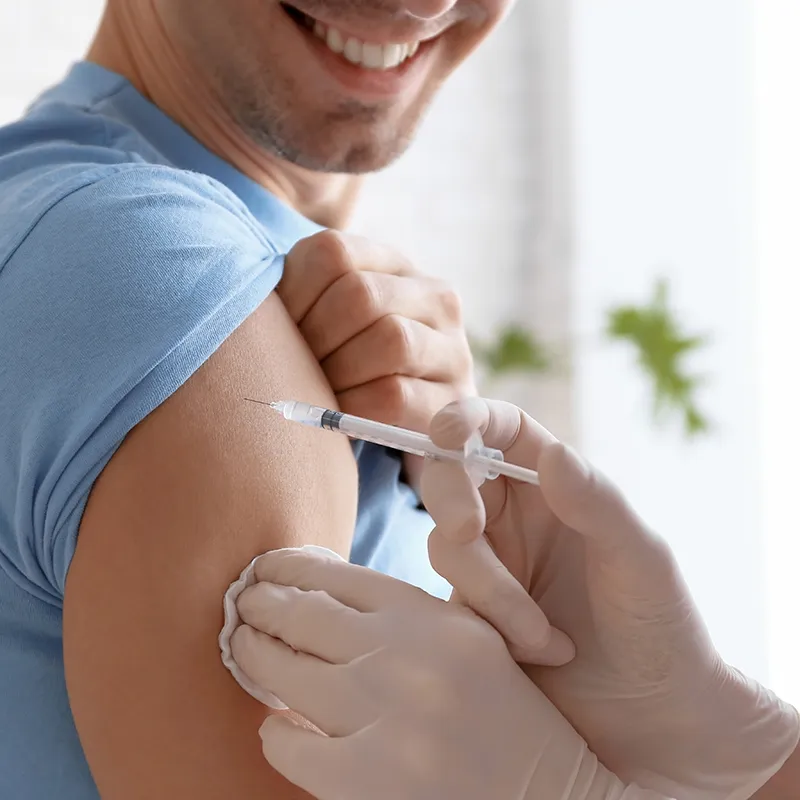 A smiling patient receiving an injection in the arm