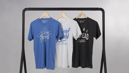 blue, white, and black shirts hanging on rack in front of white backdrop j