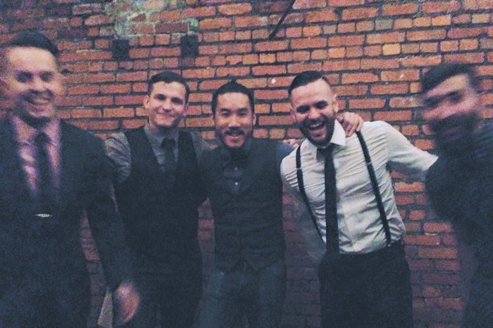 group of men standing in front of brick wall