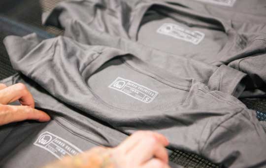 man inspecting grey shirt with tag print