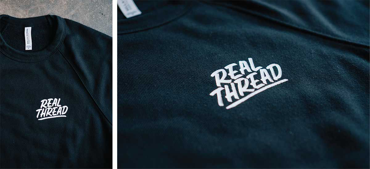 close up of white hand lettering logo on black sweater 