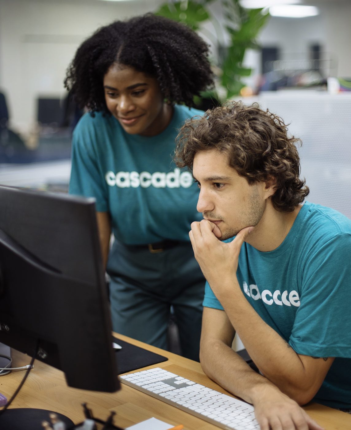 Two people wearing matching custom branded shirts work together at the computer.