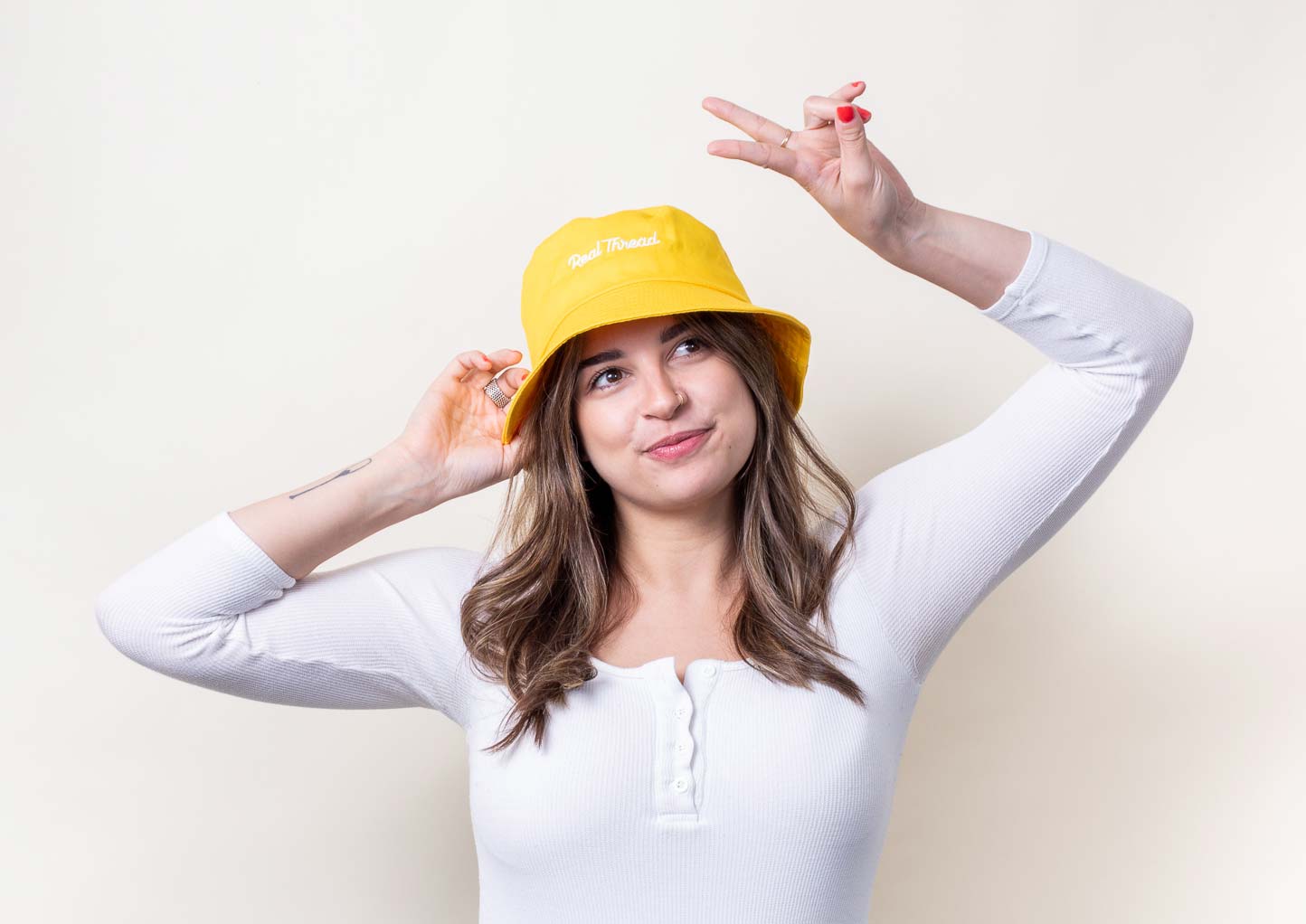 Woman wears yellow bucket hat and has a peace sign