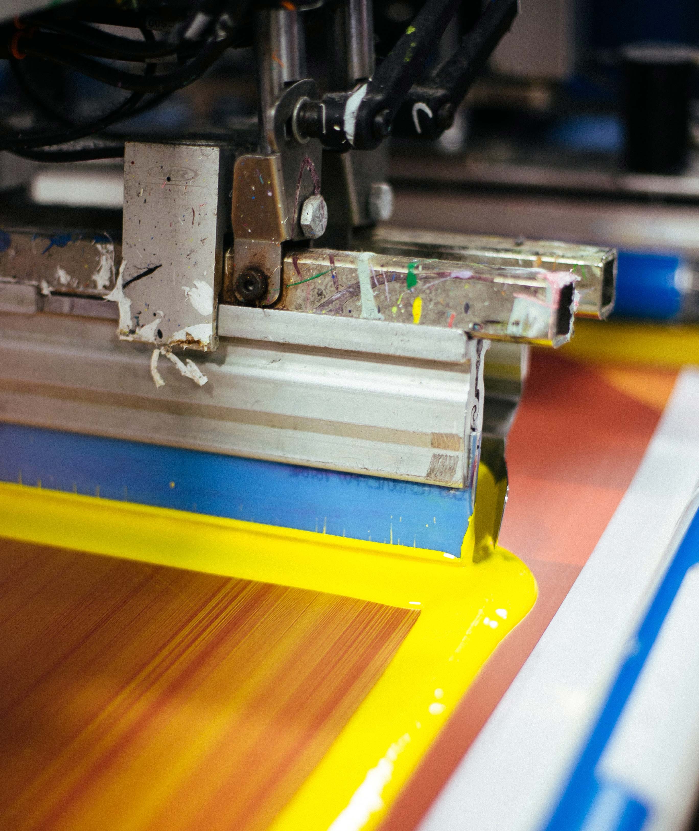 A screen printing machine spreads yellow ink across a screen