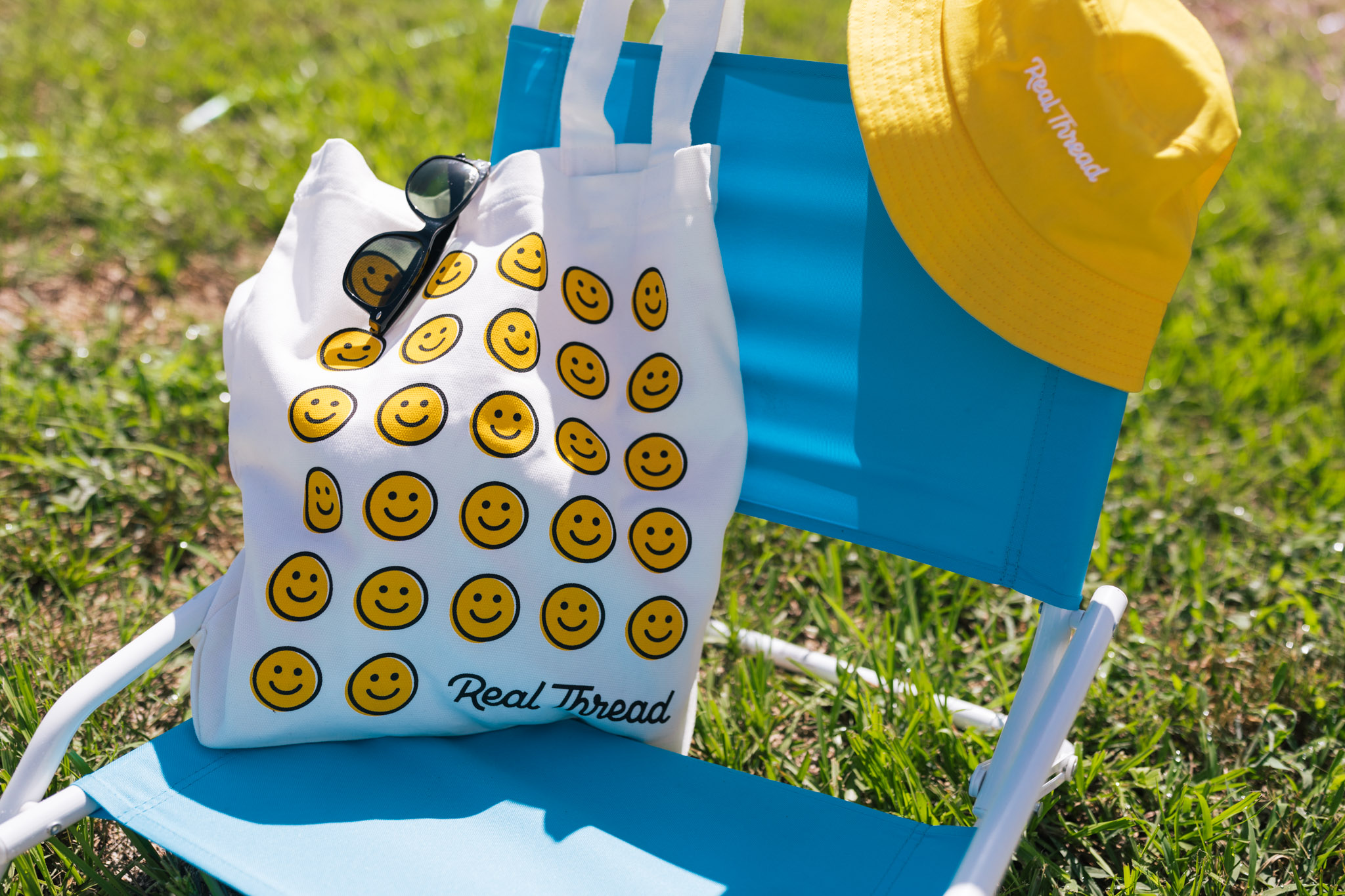 A beach chair with a custom tote bag and a custom beanie, both with fun pops of Real Thread yellow.