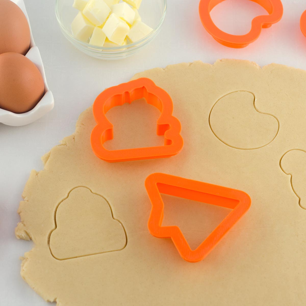 cookie cutters cutting into rolled out cookie dough