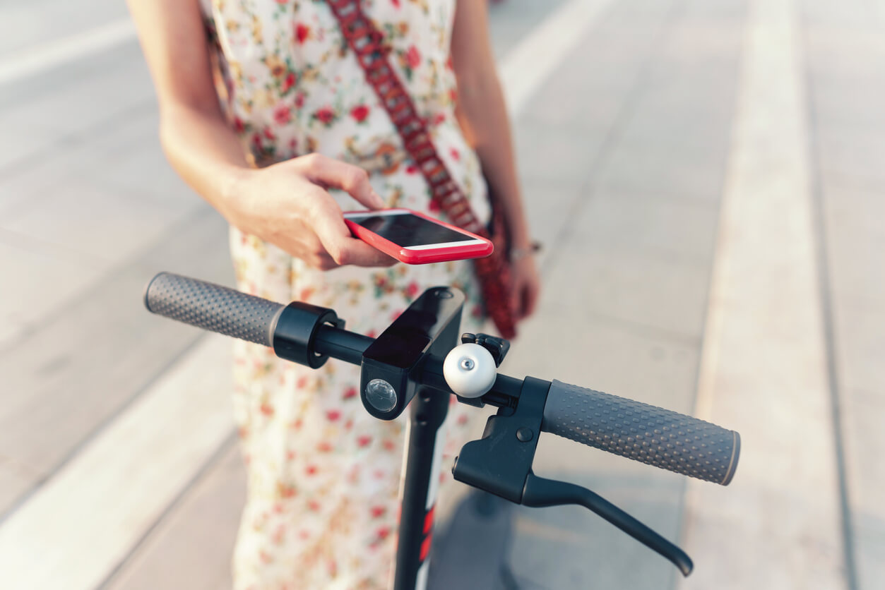 A woman unlocks a smart scooter with her iPhone