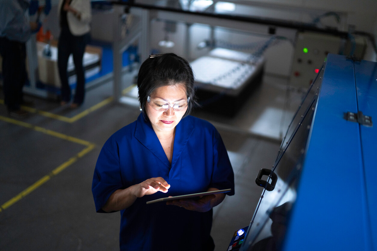 A woman oversees manufacturing from a tablet