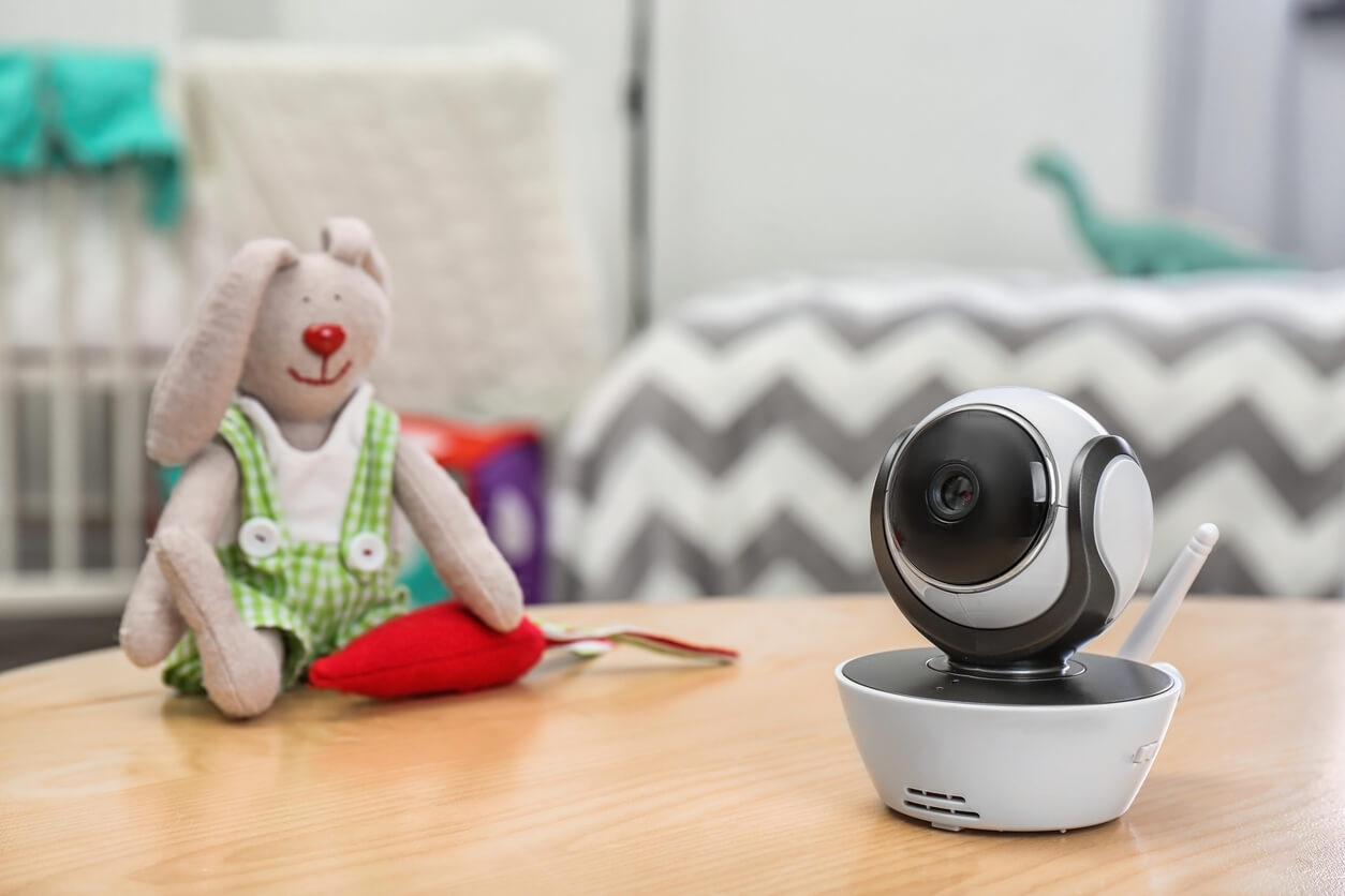 A smart baby monitor camera sits on a table next to a child's toy