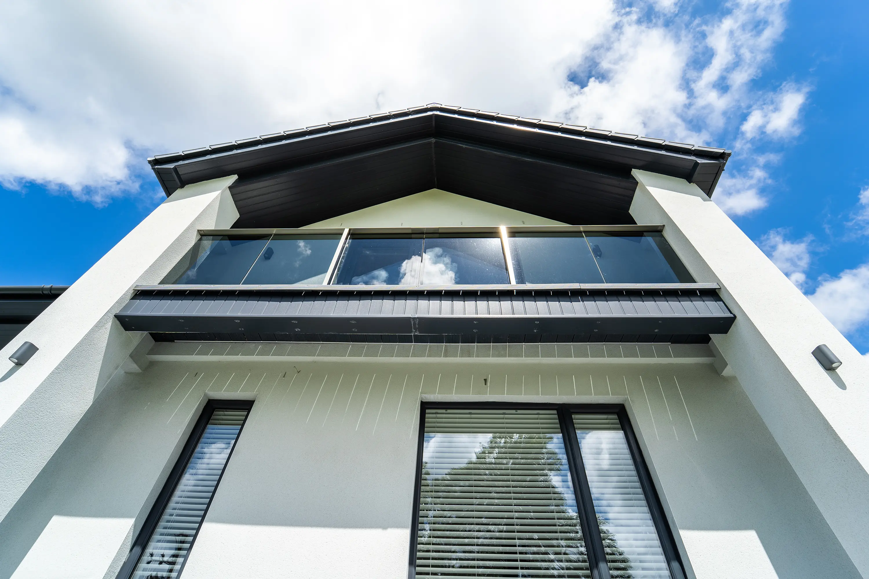 Glass balcony on contemporary lake district home viewed from below by WK Design Architects in Cumbria