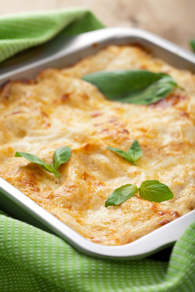 Posé sur un torchon vert se trouve un plat à gratin de forme carré, contenant la citrouille, les champignons et le poulet.