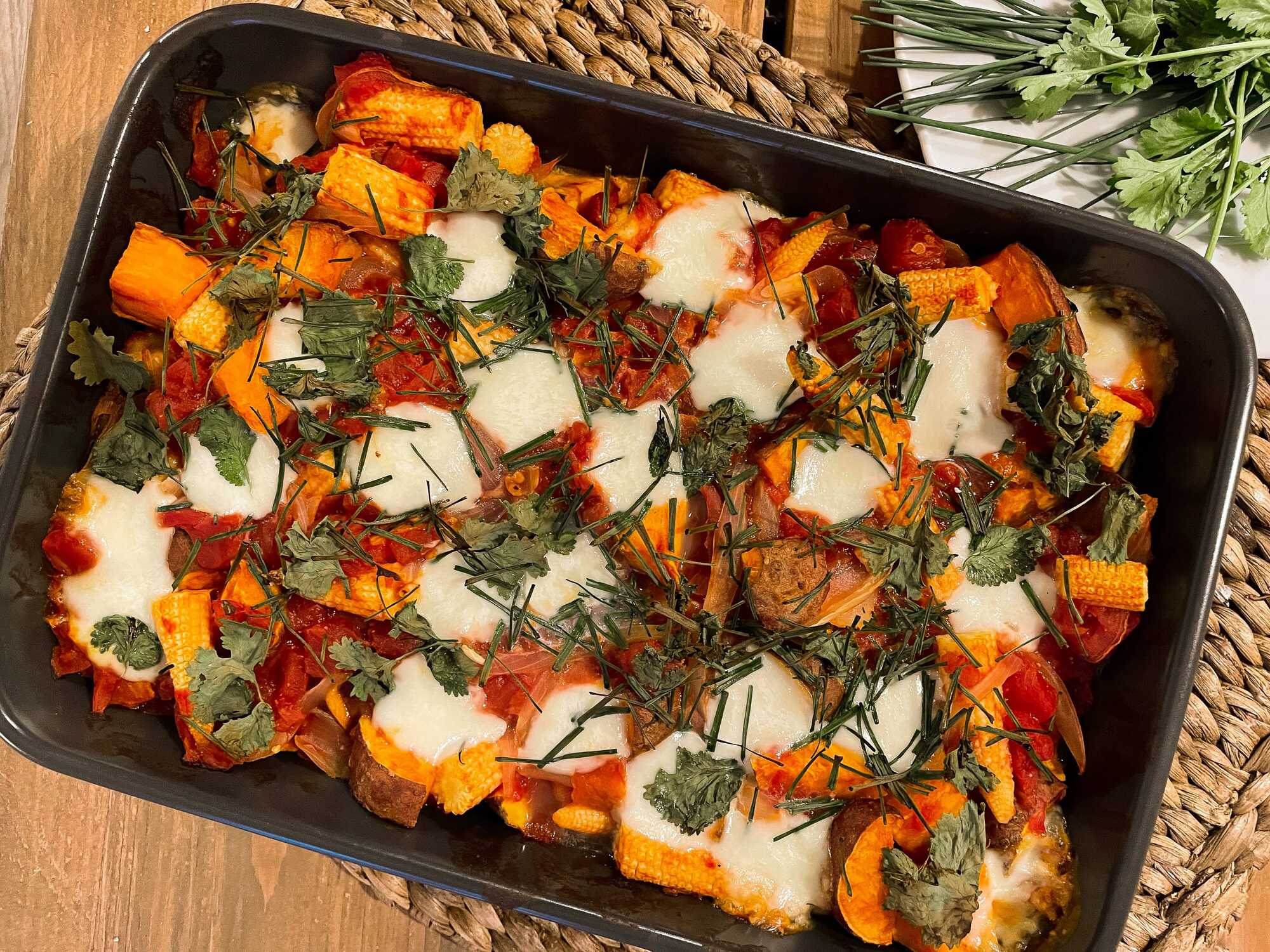 La recette de patates douces rôties aux boulettes de boeuf est exposée dans un plat à gratin avec quelques herbes aromatiques pour la décoration.