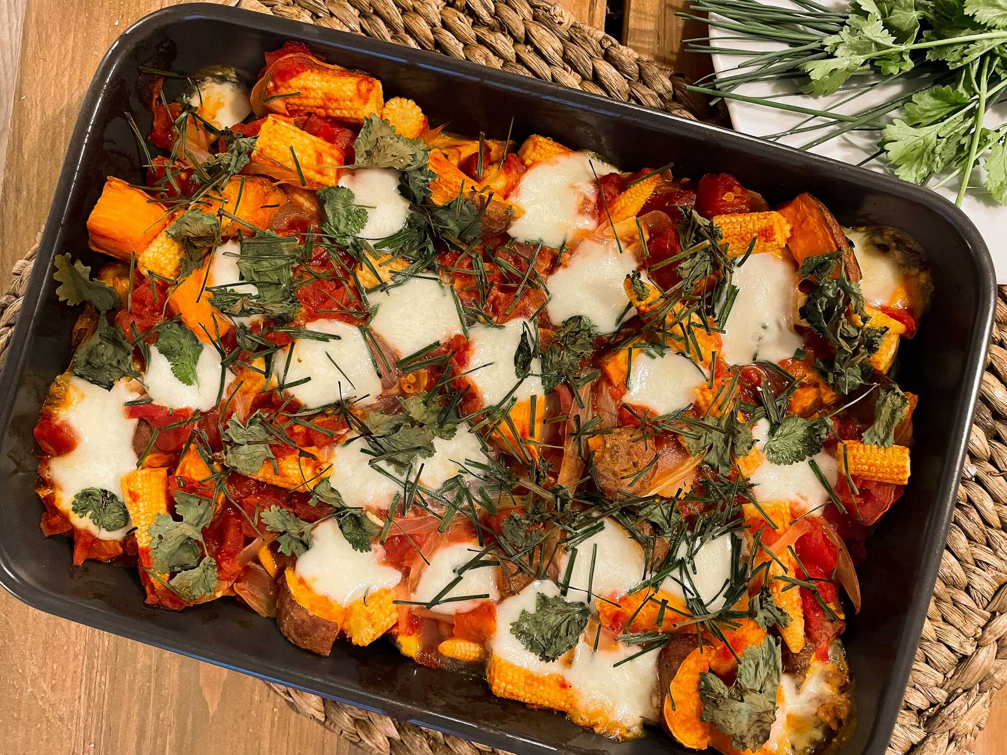 La recette de patates douces rôties aux boulettes de boeuf est présentée dans un plat à gratin avec quelques herbes aromatiques pour la décoration.