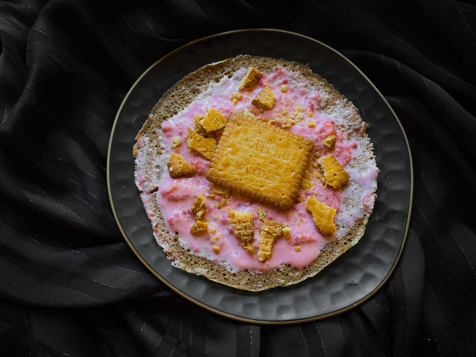 Au fond d'un petit saladier se trouve le pancake à la farine d'avoine, fraises et Petit Lu émietté. Un biscuit entier est posé sur le dessus.