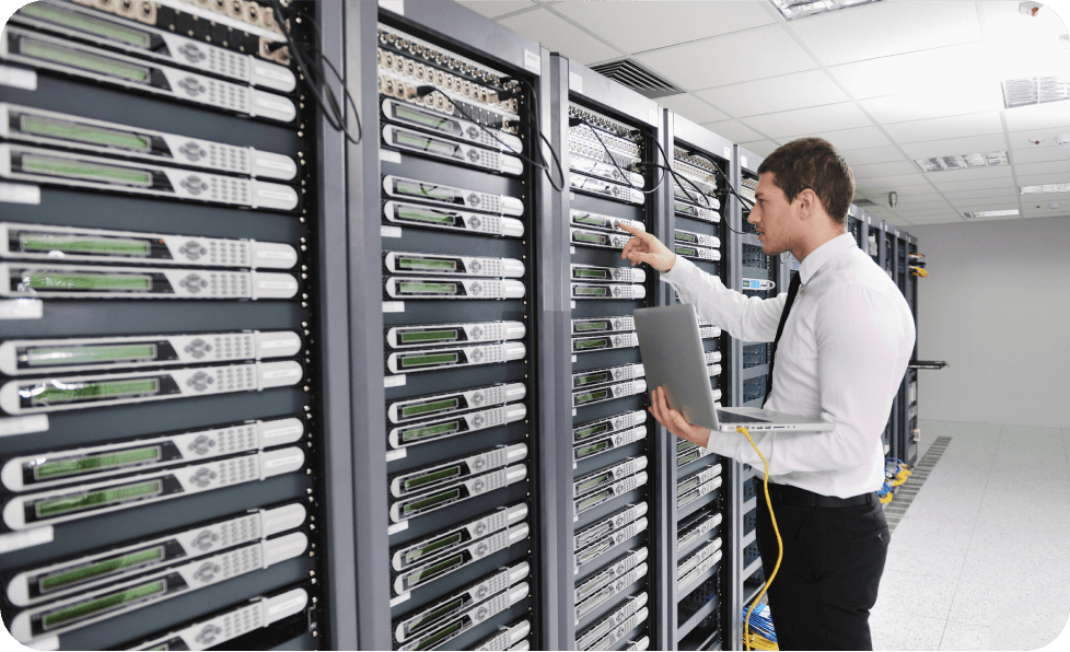 Man with laptop standing next to servers