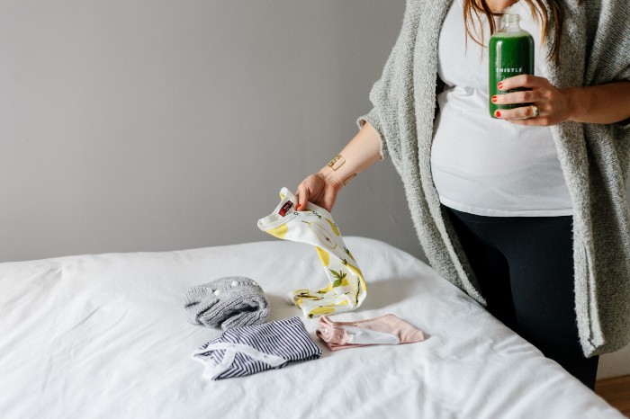 pregnant woman choosing baby clothes