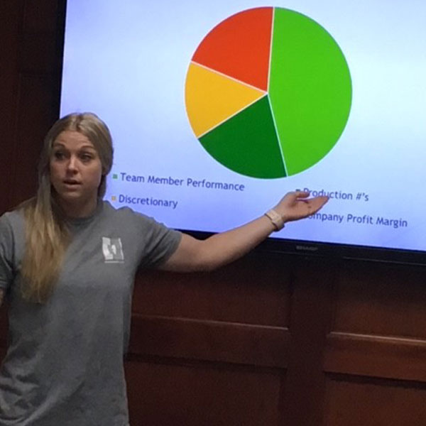 Employee, Chelsea, pointing at a pie chart during a training meeting.