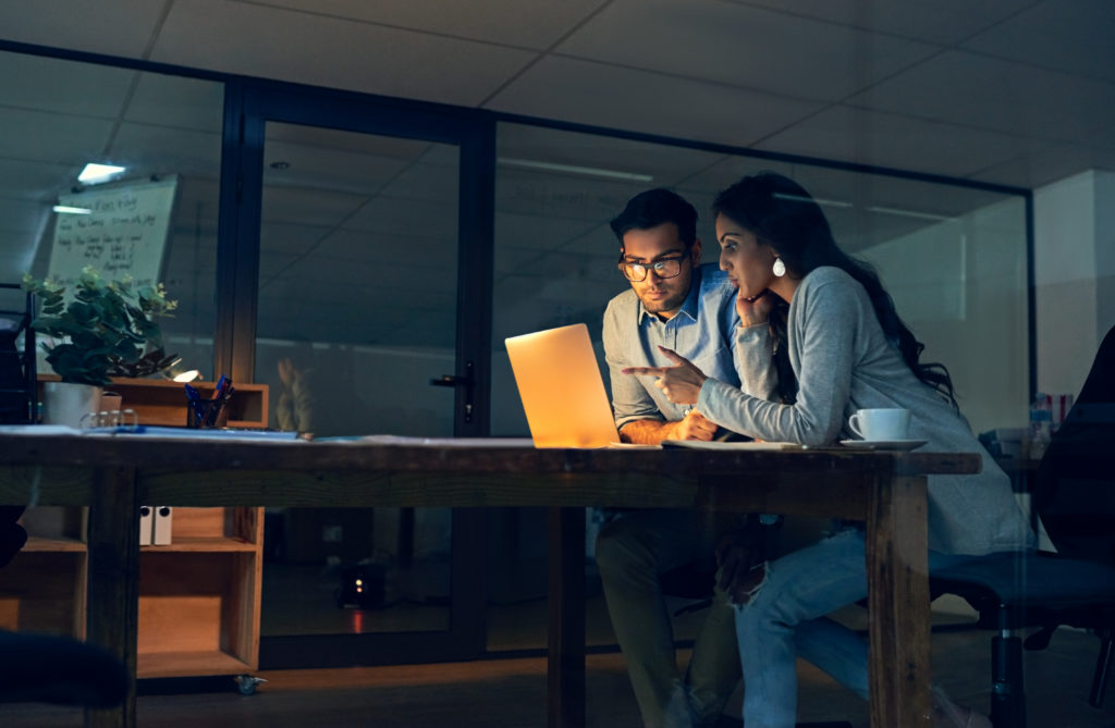 Coworkers collaborate in front of a laptop computer