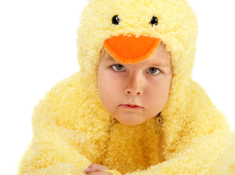 A young child in a chicken costume looking disappointed.