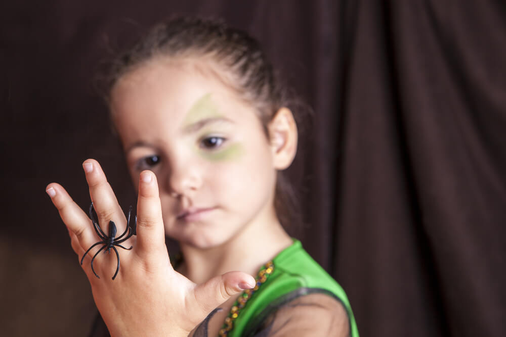 A young girl with a plastic spider ring on her finger.