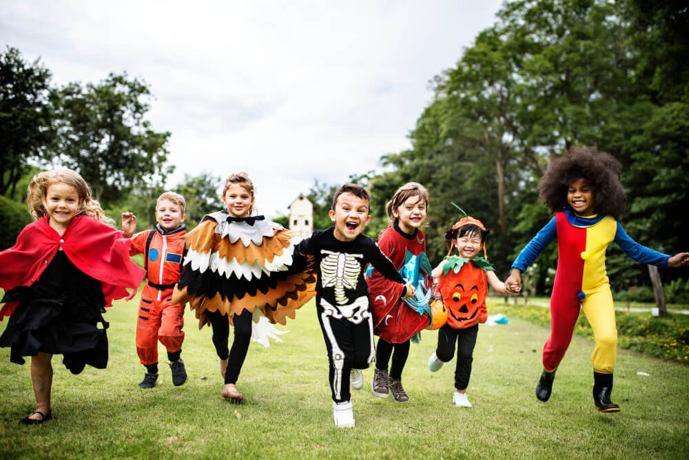 A group of children running towards the camera with Halloween costumes on.