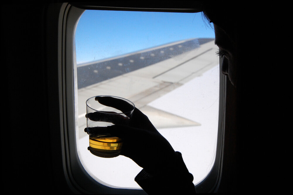 A person drinking alcohol on a plane.