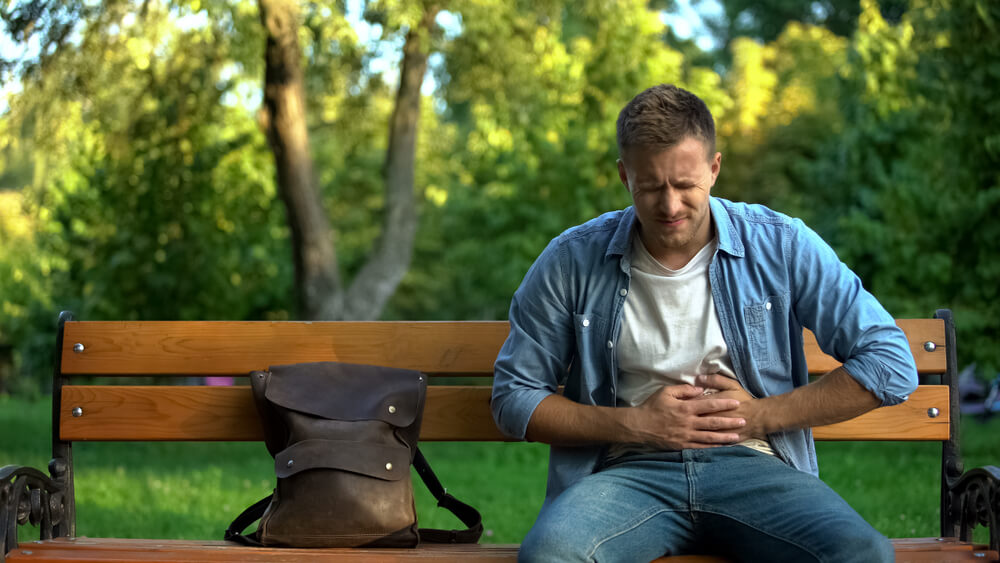 A person on a bench feeling sick.